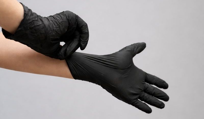 Eine Hand zieht einen blauen Latexhandschuh an.